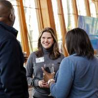 Laura Aikens standing with chatting with two event guests